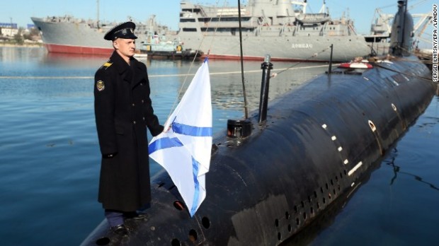 A Russian sailor holds the Russian Navy's St. Andrew flag while standing on the bow of the surrendered Ukrainian submarine Zaporozhye in Sevastopol, Crimea, on Saturday, March 22. 