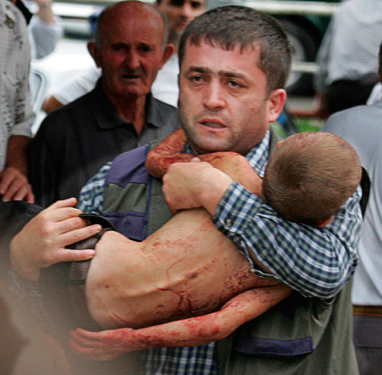 A man carries a wounded child out of a school building seized by terrorists in Beslan in 2004. Photo: Ivan Sekretaryev/AP