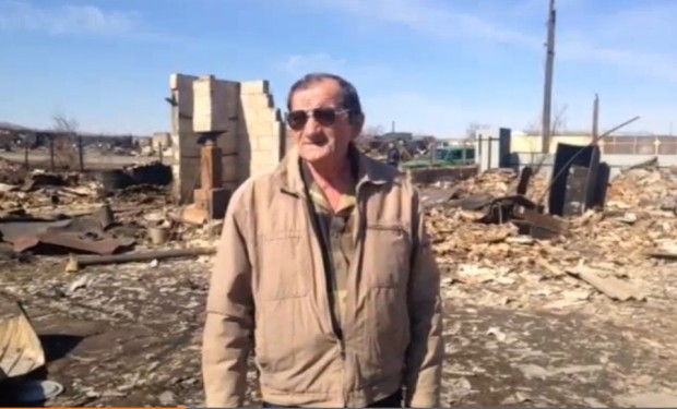A man stands in the burnt ruins of his home in Novokursk after wildfires swept through the town in April 2015. He appealed to the president for help in a video address to Pryamaya Liniya.